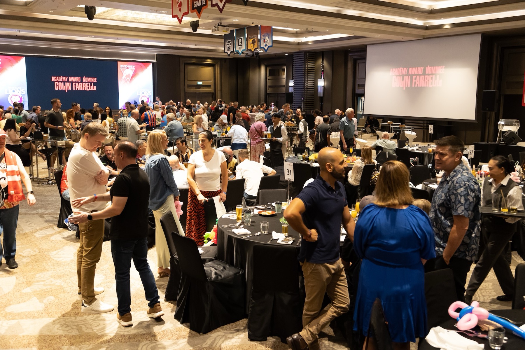 A full function room at a Chamber event with sponsor branding on the screens