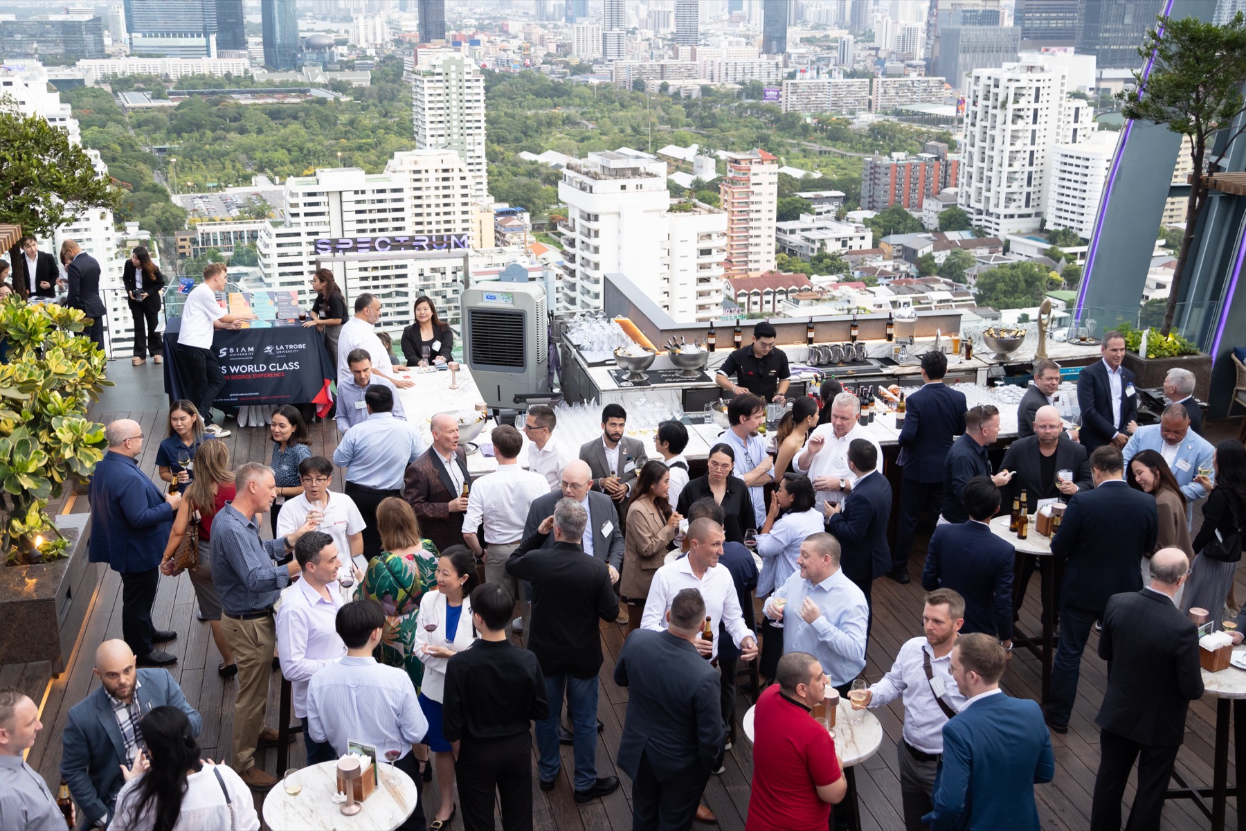 Guests on a rooftop terrace with the Bangkok skyline behind them